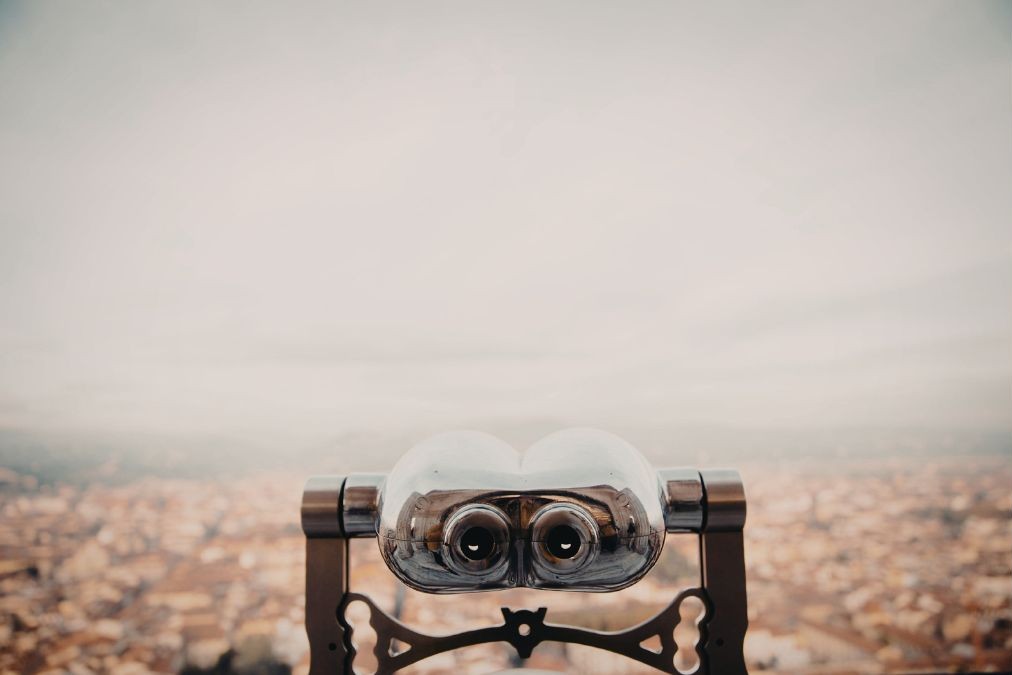 Viewing telescope overlooking a distant city at sunset, symbolizing why resolutions fail when people lack vision and awareness of their ongoing personal transformation and growth.