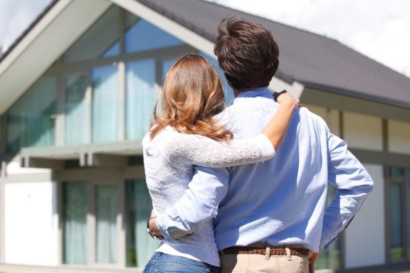 Happy man and woman lookiing at their new home together while smiling, symbolizing progress, reflection, and the idea that why resolutions fail is not always about missing a goal, but failing to recognize growth happening in other meaningful ways.